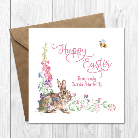 A personalised Easter card with an illustration of an Easter bunny surrounded by spring flowers, with pink writing on the front