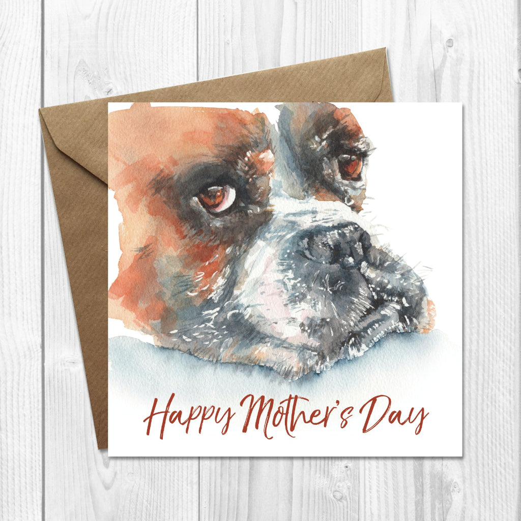 Greeting card with a boxer dog's face illustration and 'Happy Mother's Day' text on a wooden surface.