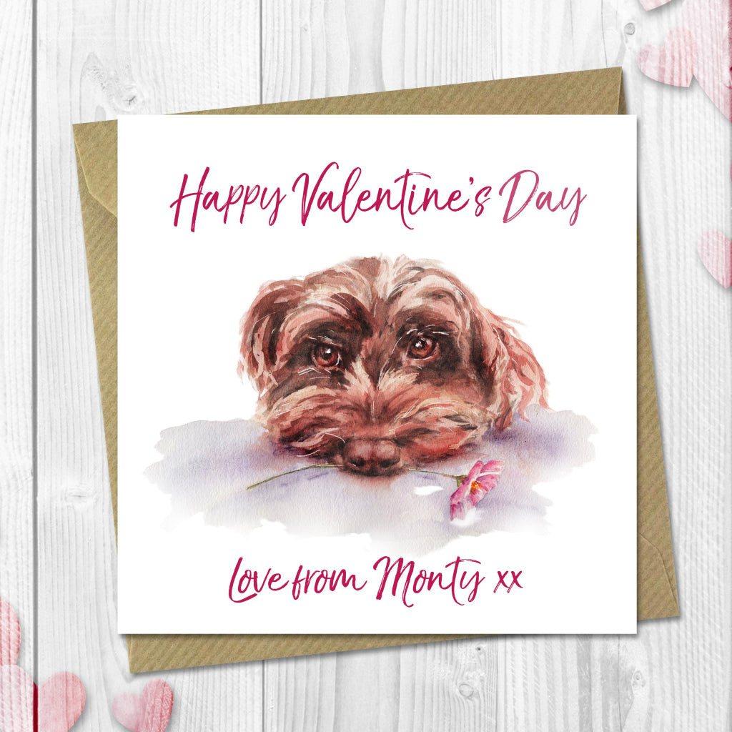 Valentine's Day card with a cockerpoo dog illustration and 'Happy Valentine's Day' text on a wooden surface with heart decorations.