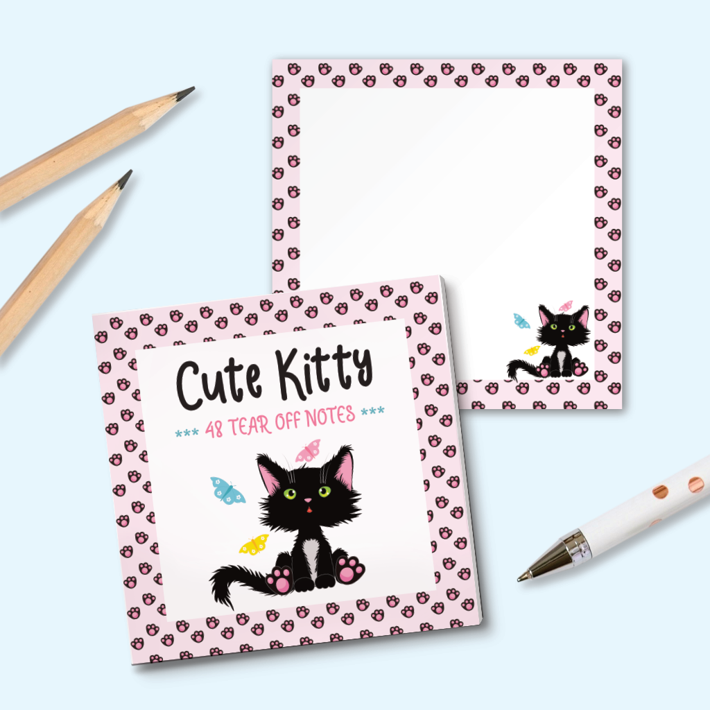 A square tear-off note pad  with a cute black kitten illustration and pink patterned borders, styled on a light blue background with two wooden pencils and a white pen. An example page with a smallet cat illustration and pink paw print pattern is shown