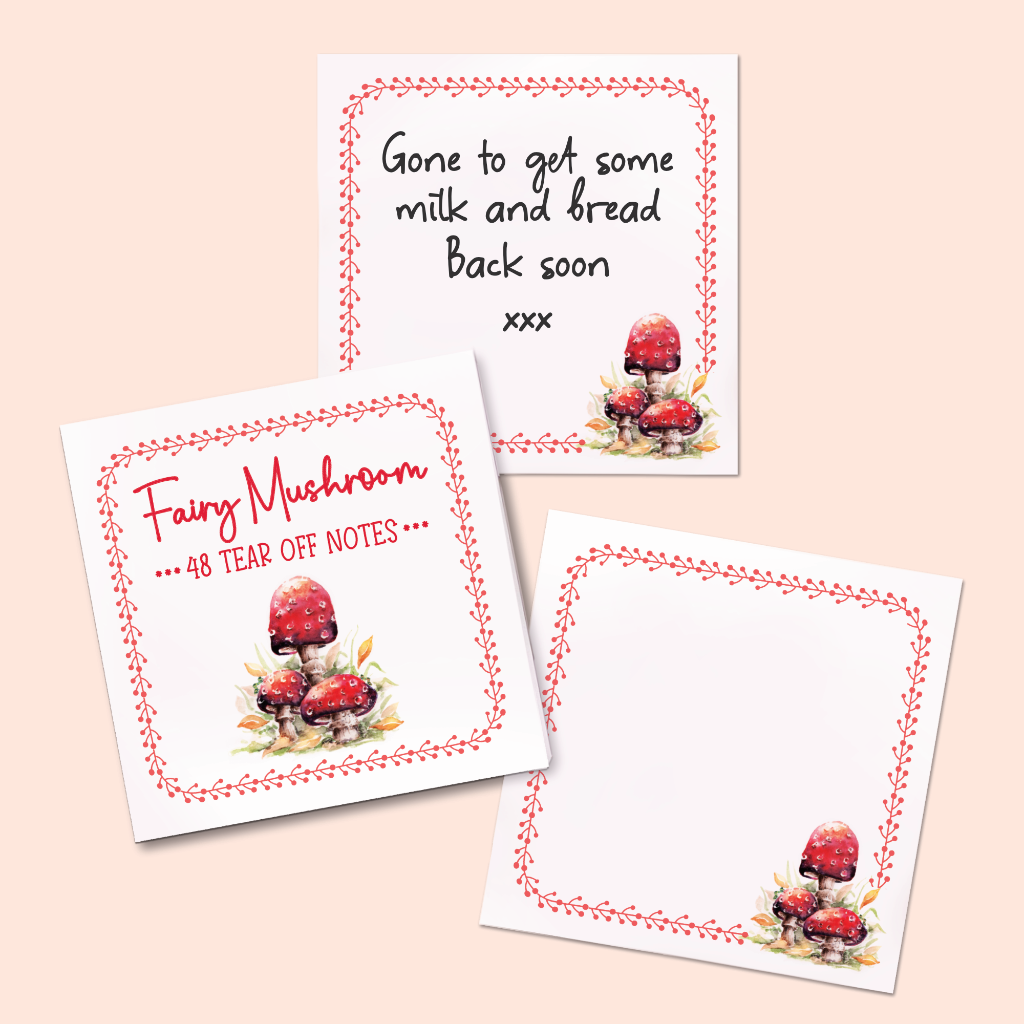 Two white tear-off note cards with red mushroom watercolor illustrations and decorative red dotted borders, arranged on a pale peach background. One card shows a usage example of written text  'Gone to get some milk and bread Back soon xxx'. The other is  picture of the cover of the fairy mushroom memo pad, saying it has 48 tear off notes