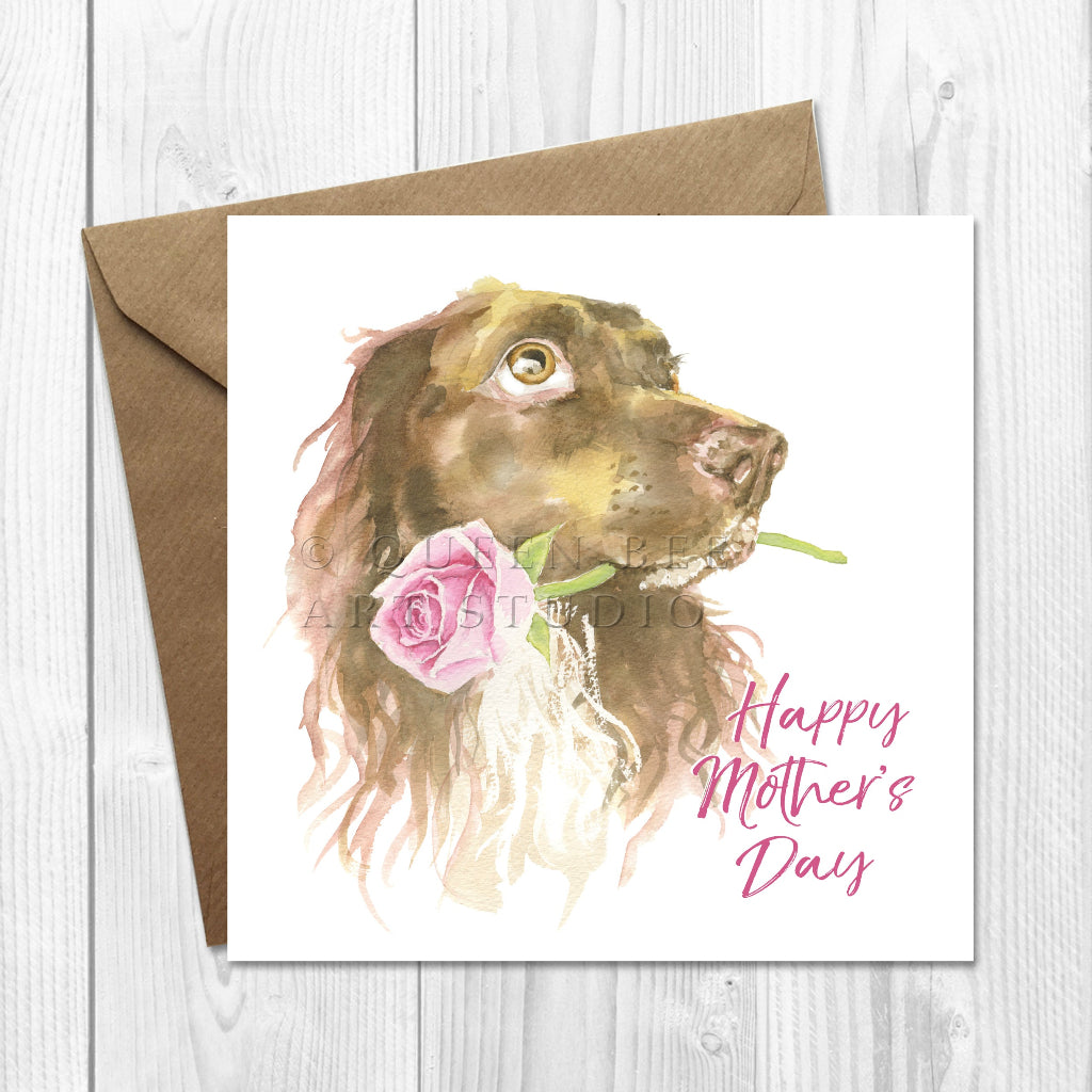 Greeting card with a brown spaniel dog illustration and 'Happy Mother's Day' text on a wooden surface.