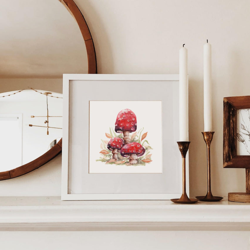 small square picture of red fairy toadstools on an autumnal mantelpiece shelf