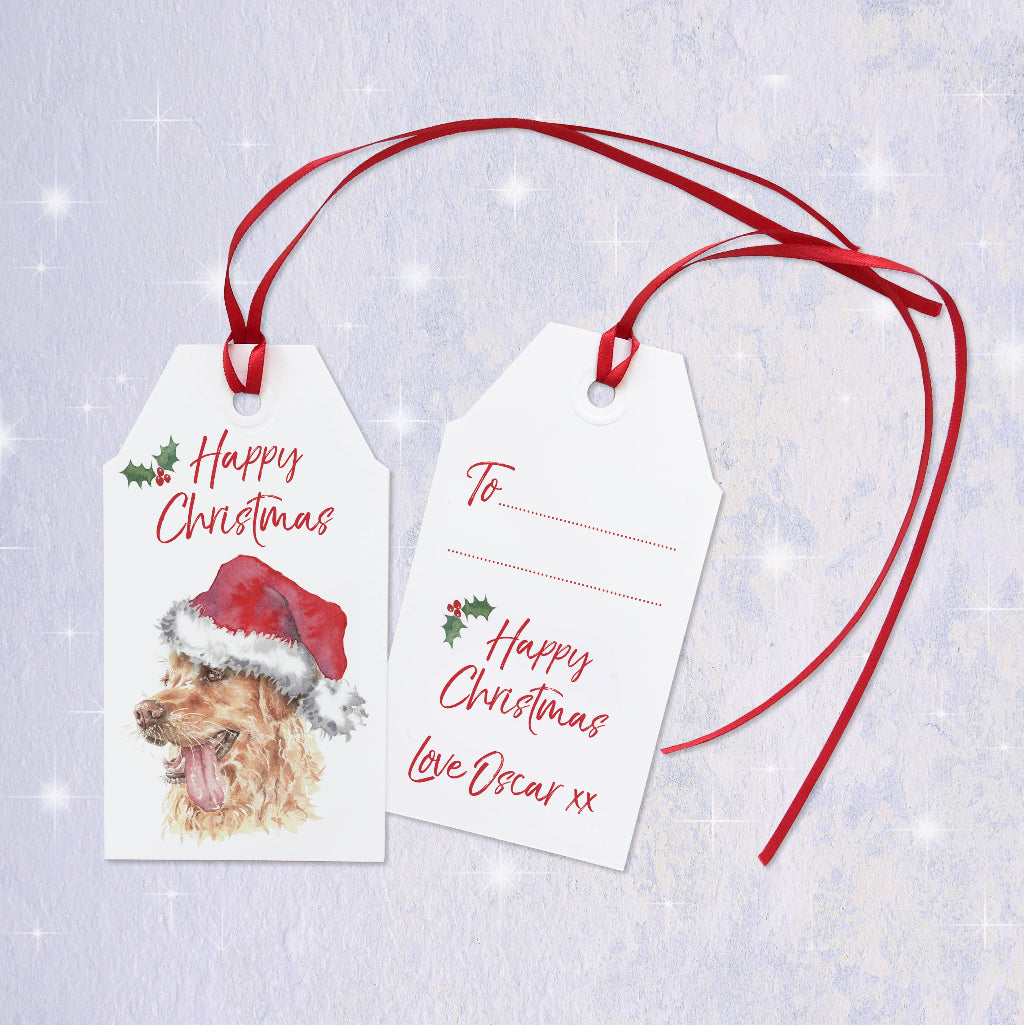 A Christmas gift tag with a golden retriever dog wearing a Santa hat. The gift label can be personalised on the reverse with dog's name