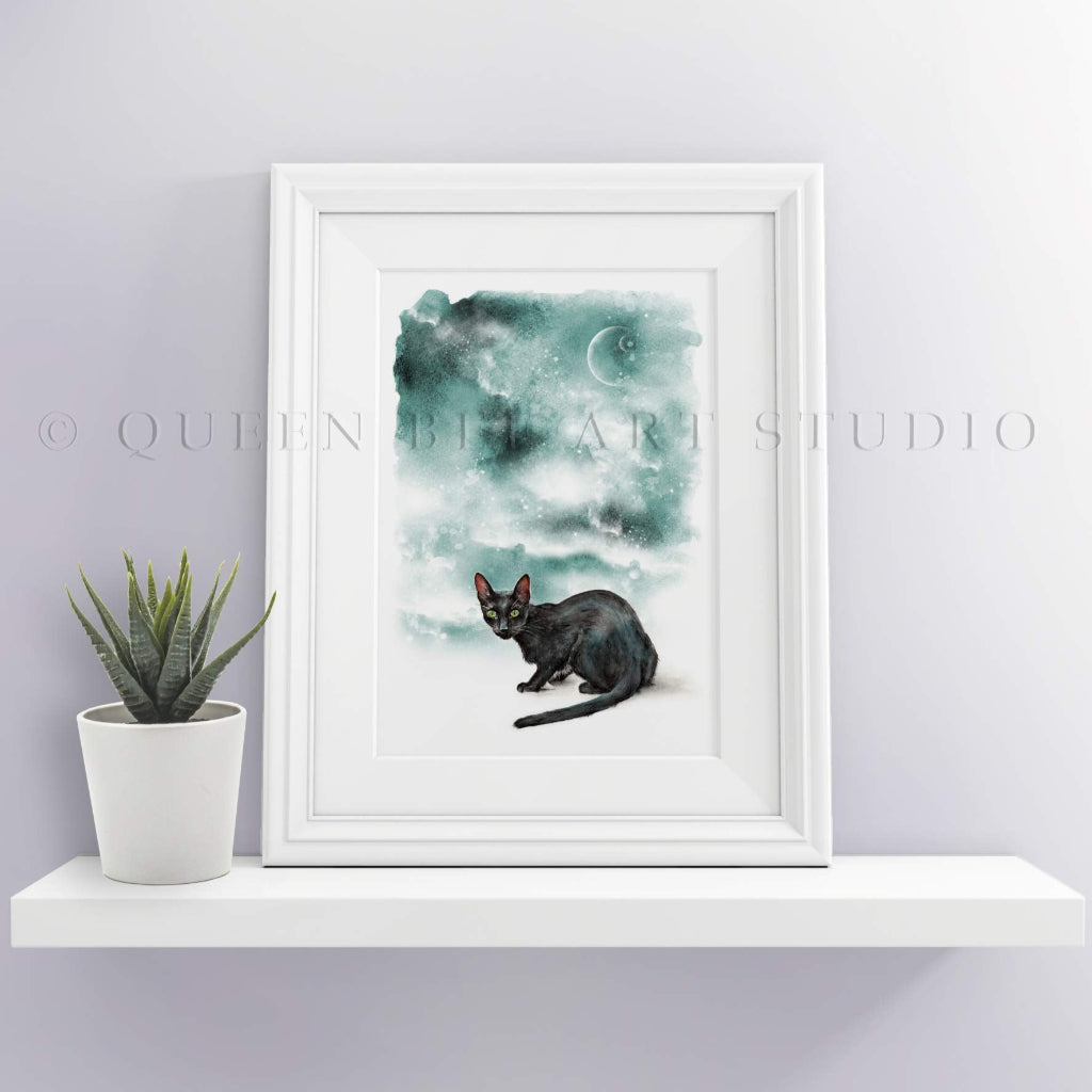 small framed picture on shelf of slinky black cat with eerie dark green sky with moom, stars and galazy