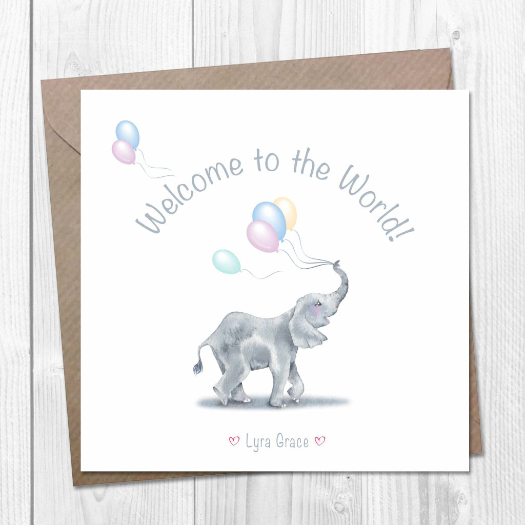 A cute drawing of a baby elephant holding colorful balloons with its trunk on a greeting card. "Welcome to the World!" is written above it. The card is personalised with a baby's name on the front.