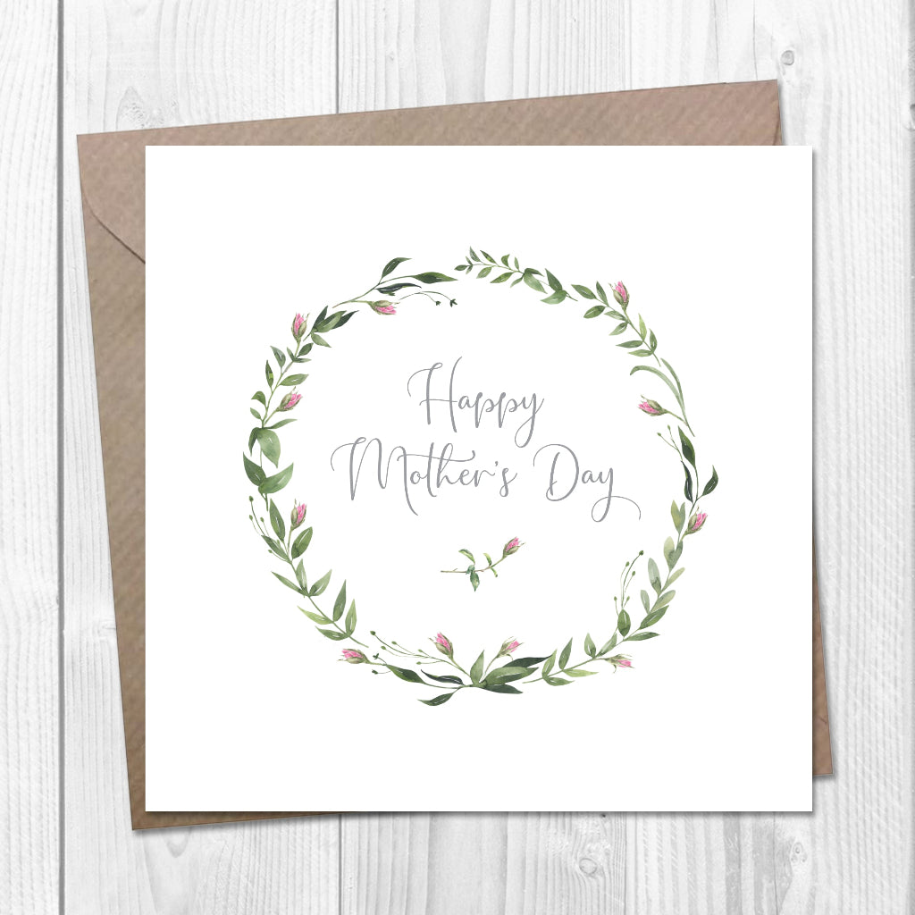 Greeting card with floral wreath and 'Happy Mother's Day' text on a wooden surface